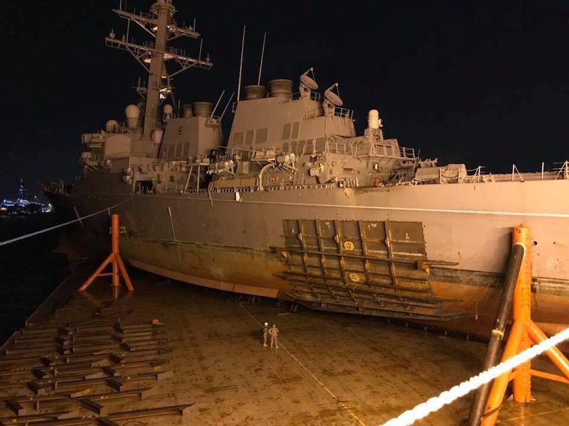 USS John S. McCain sits aboard MV Treasure as it is prepared to sail to Japan for repairs. The extent of the damage can be seen. USN photo.